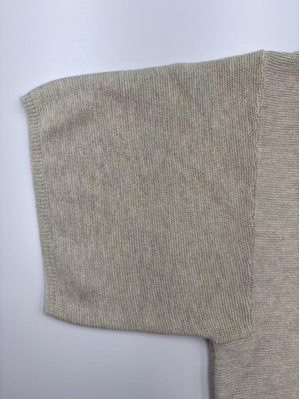 Close-up of beige knit sweater sleeve showing fine texture and stitching, ideal for fashion and clothing SEO.