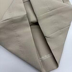 Close-up of a neatly folded beige fabric with smooth texture, ideal for fashion or home decor projects.