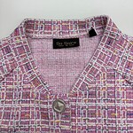 Close-up of a pink tweed women's jacket with a silver button, featuring a textured pattern and a black label inside reading 'So Soire' for fashion and style.