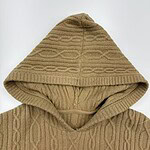 Close-up of a beige cable knit hoodie with a hood, showcasing detailed knitting patterns and texture, perfect for casual winter wear.
