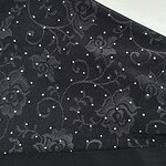 Close-up of black lace fabric featuring intricate floral embroidery and small sparkling embellishments, ideal for fashion and evening wear.