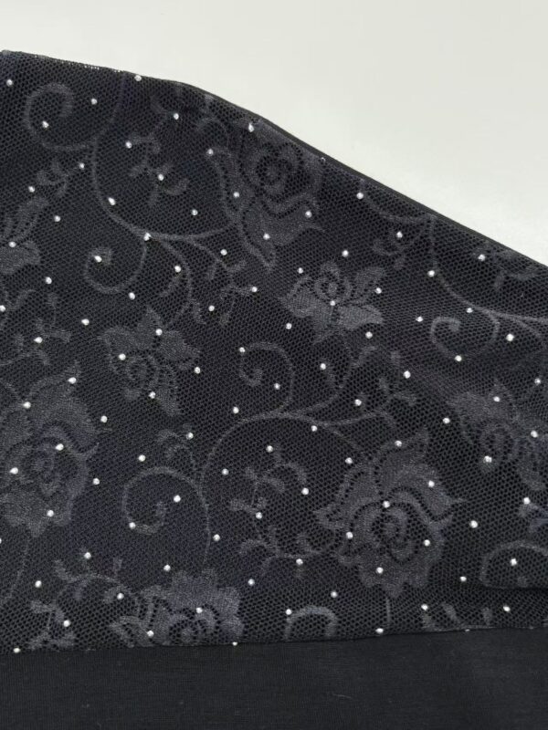 Close-up of black lace fabric featuring intricate floral embroidery and small sparkling embellishments, ideal for fashion and evening wear.