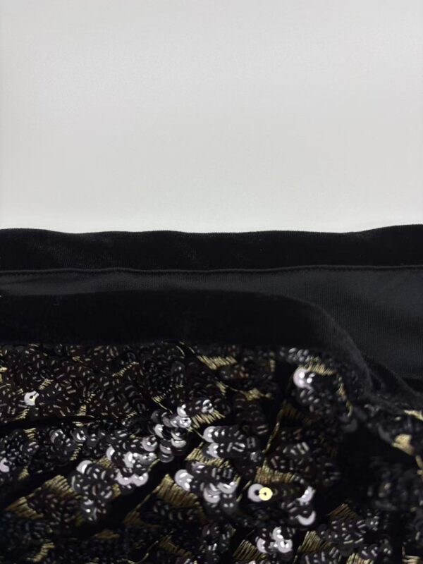 Close-up of a fabric featuring intricate embroidery and shiny sequins, suitable for stylish clothing or accessories.