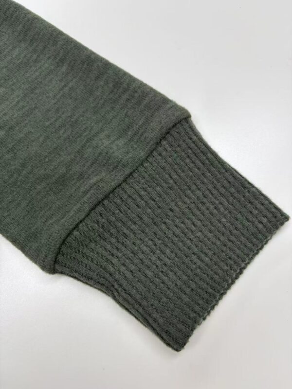 Close-up of a green sweatshirt sleeve with ribbed cuff, showcasing comfortable casual wear for men and women.