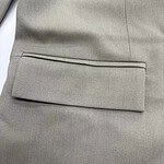 Close-up of a beige suit jacket pocket with clean stitching and tailored design, ideal for formal or business attire.