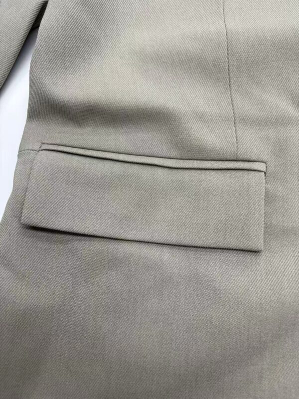 Close-up of a beige suit jacket pocket with clean stitching and tailored design, ideal for formal or business attire.