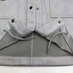 Close-up of grey cargo pants featuring multiple pockets, button details, and drawstring waist for a modern, casual look.
