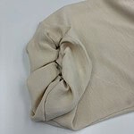 Close-up of a beige casual sweater with rolled-up sleeves, made of soft fabric, suitable for everyday wear and stylish comfort.