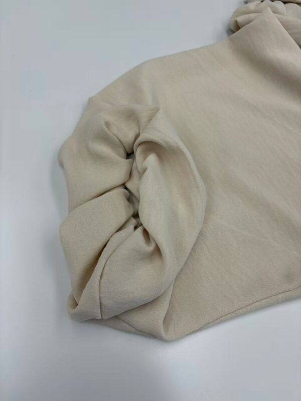 Close-up of a beige casual sweater with rolled-up sleeves, made of soft fabric, suitable for everyday wear and stylish comfort.