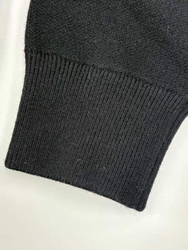 Detailed view of a black sweater cuff showing ribbed knit texture and fabric quality, ideal for fashion and clothing product listings.
