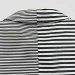 Close-up of a black and white striped shirt with a collar, showcasing contrasting stripe patterns on each side.