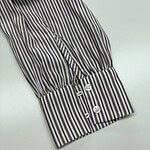 Close-up of a striped shirt cuff featuring vertical multicolor stripes and four white buttons, showcasing stylish and elegant design details.