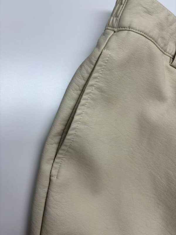 Close-up of beige casual men's pants showing fabric texture and stitching details, suitable for everyday wear and fashion.