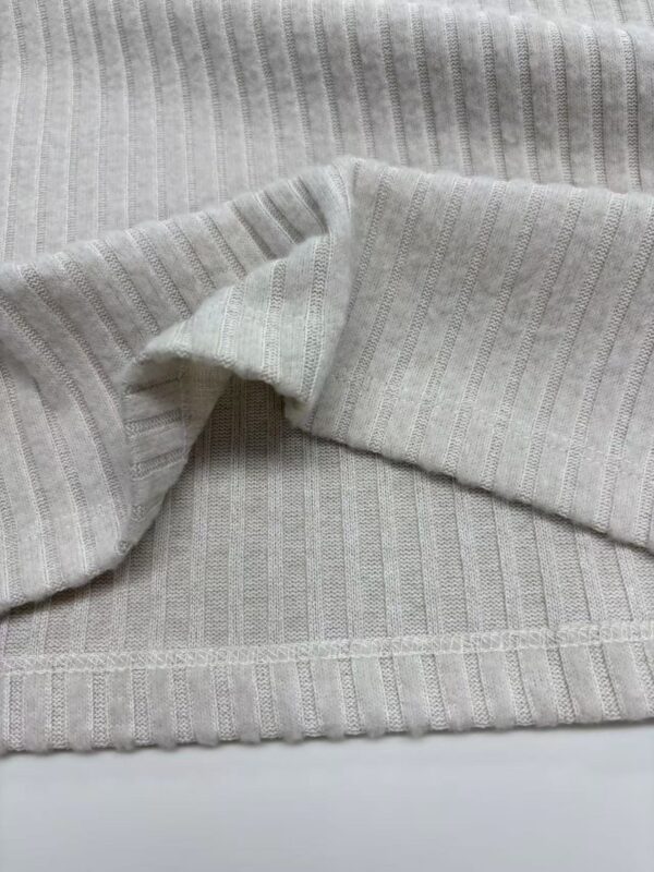 Close-up of light gray ribbed knit fabric, showcasing its texture and fine vertical lines, ideal for sweaters and casual wear.
