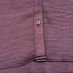 Detailed view of mauve button-down shirt fabric with buttons and stitching, showcasing casual fashion style.