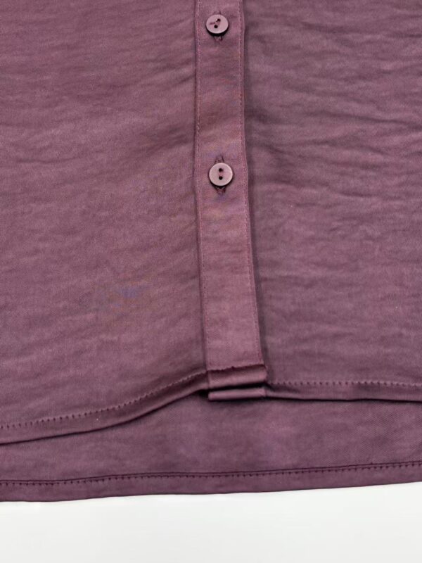 Detailed view of mauve button-down shirt fabric with buttons and stitching, showcasing casual fashion style.
