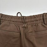Close-up of brown casual pants featuring an elastic waistband, belt loops, and two front pockets, suitable for everyday wear.