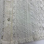 Close-up of intricate white lace fabric with floral and geometric patterns, suitable for wedding dresses and elegant fashion designs.