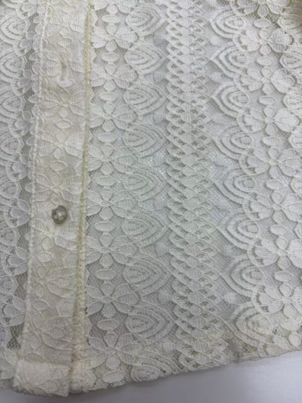 Close-up of intricate white lace fabric with floral and geometric patterns, suitable for wedding dresses and elegant fashion designs.