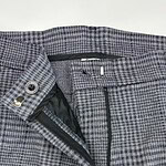 Close-up of men's checked dress pants with zipper and button closure, suitable for business or formal occasions.