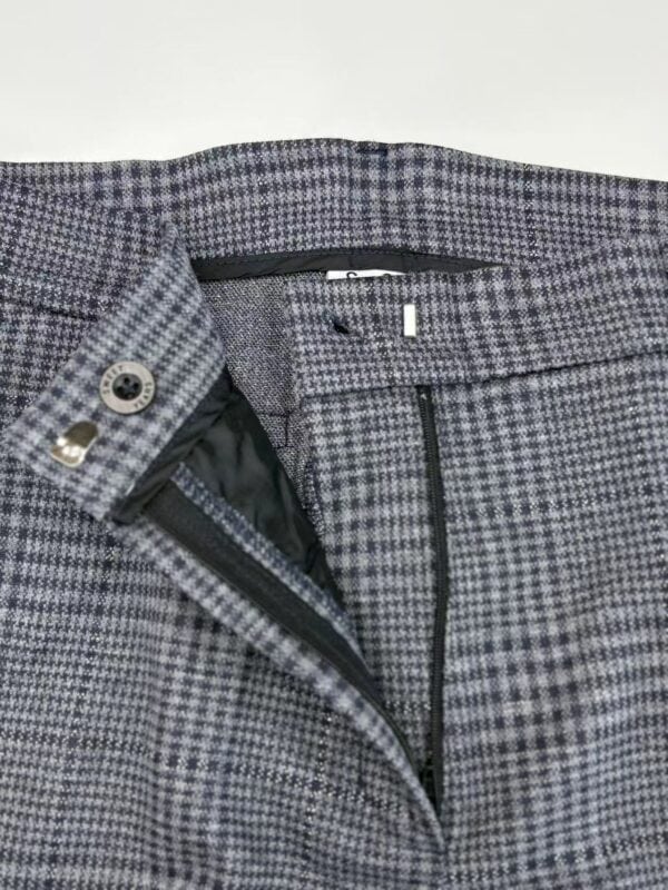 Close-up of men's checked dress pants with zipper and button closure, suitable for business or formal occasions.