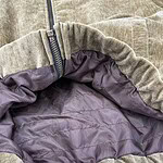 Close-up of a beige casual hoodie with a zipper and purple lining, showcasing comfortable fabric and stylish design.