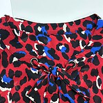 Close-up of a stylish animal print blouse with a bow tie detail, featuring red, black, white, and blue colors, perfect for fashion-forward outfits.