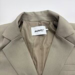 Close-up of a beige women's blazer with a notched lapel, tailored fit, and smooth fabric, perfect for professional or casual wear.
