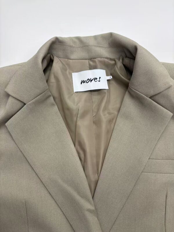 Close-up of a beige women's blazer with a notched lapel, tailored fit, and smooth fabric, perfect for professional or casual wear.