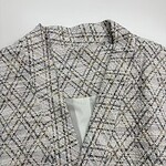Close-up of a stylish women's tweed blazer with a classic checkered pattern, perfect for professional or casual wear.