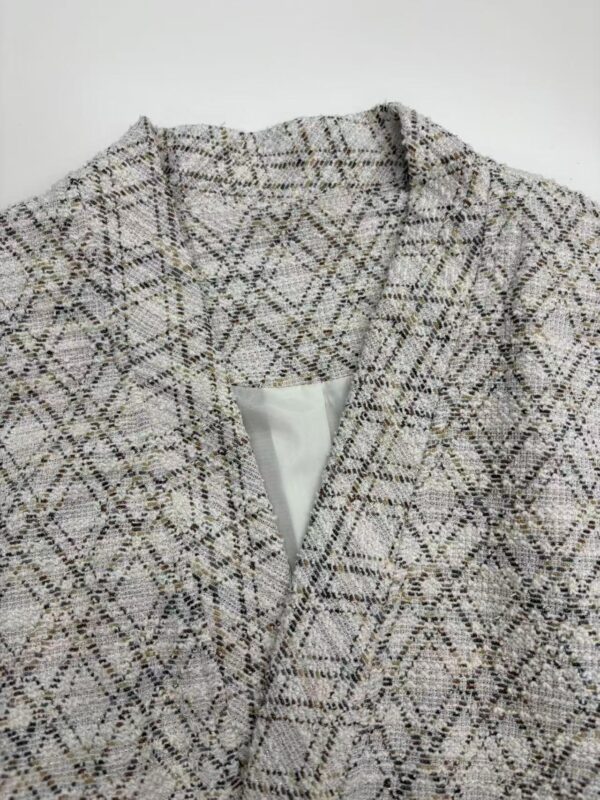 Close-up of a stylish women's tweed blazer with a classic checkered pattern, perfect for professional or casual wear.
