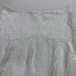 Elegant white lace skirt with intricate floral patterns, perfect for summer or special occasions, showcasing delicate craftsmanship and stylish design.