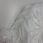 Close-up of a white lace dress with intricate embroidery and delicate fabric, perfect for weddings or formal events.