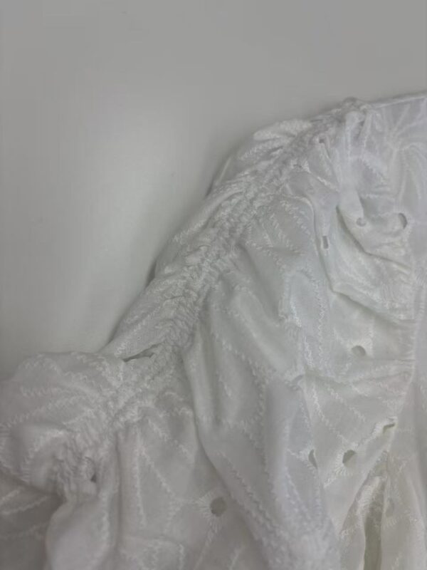 Close-up of a white lace dress with intricate embroidery and delicate fabric, perfect for weddings or formal events.