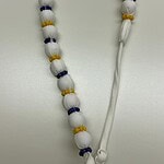 White prayer beads with yellow and blue accents, used for meditation or religious rituals, laid on a plain surface.