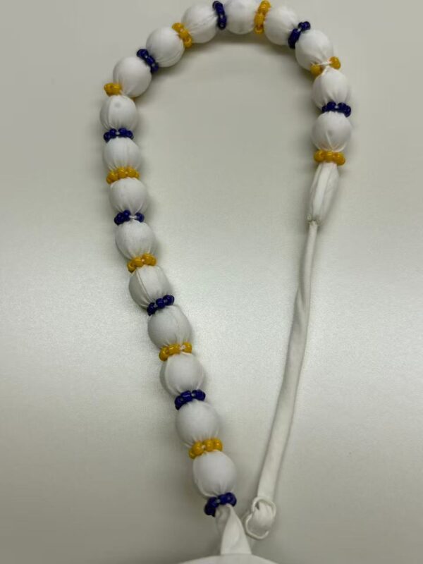 White prayer beads with yellow and blue accents, used for meditation or religious rituals, laid on a plain surface.