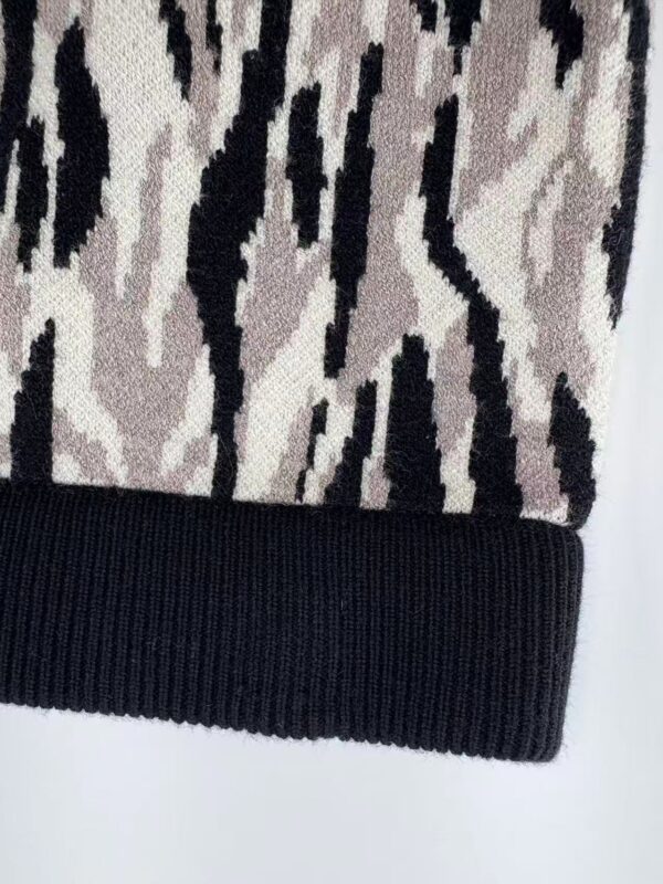 Close-up of a stylish knit beanie hat featuring a zebra print pattern in black and beige with a solid black ribbed brim, perfect for fashion and warmth.