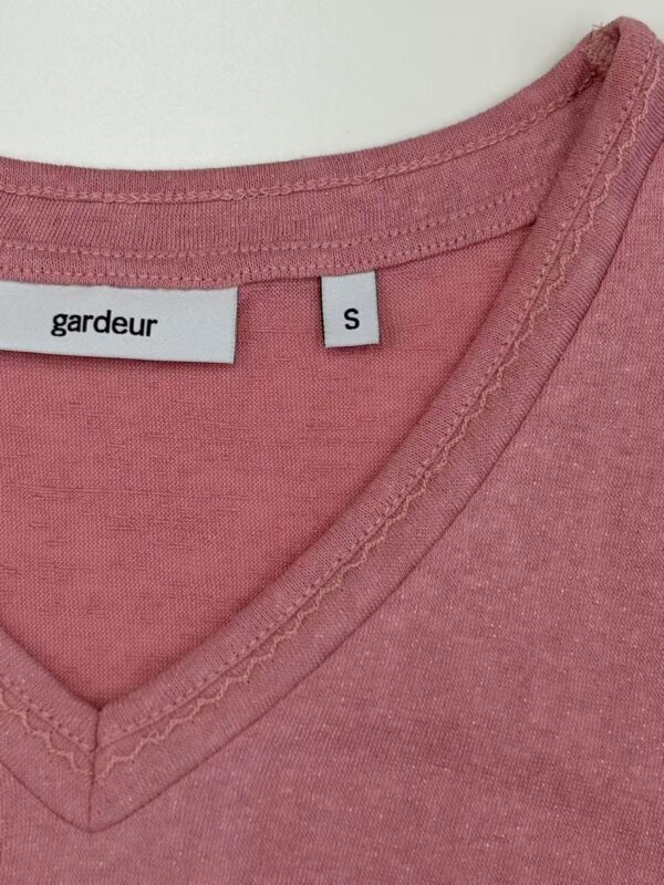 Close-up of pink V-neck T-shirt with Gardeur brand label and size S tag, showcasing soft fabric and stitching details.