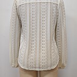 Close-up of a cream-colored lace blazer with intricate patterns, long sleeves, and a tailored fit, displayed on a mannequin against a plain background.