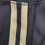 Close-up of black pants featuring beige and black vertical stripe detail, showcasing stylish and modern design elements.