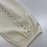 Close-up of cream lace fabric with intricate eyelet and embroidery details, ideal for fashion and apparel design.