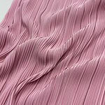 Close-up of pink pleated fabric with fine vertical lines, showcasing texture and flow, ideal for stylish clothing and fashion design.