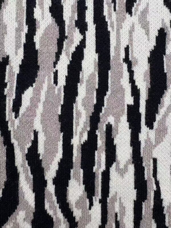 Close-up of zebra print fabric featuring black, white, and gray stripes, ideal for fashion and interior design projects.