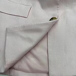 Close-up of a stylish light pink blazer with a lapel and pocket detail, perfect for formal or business casual wear.