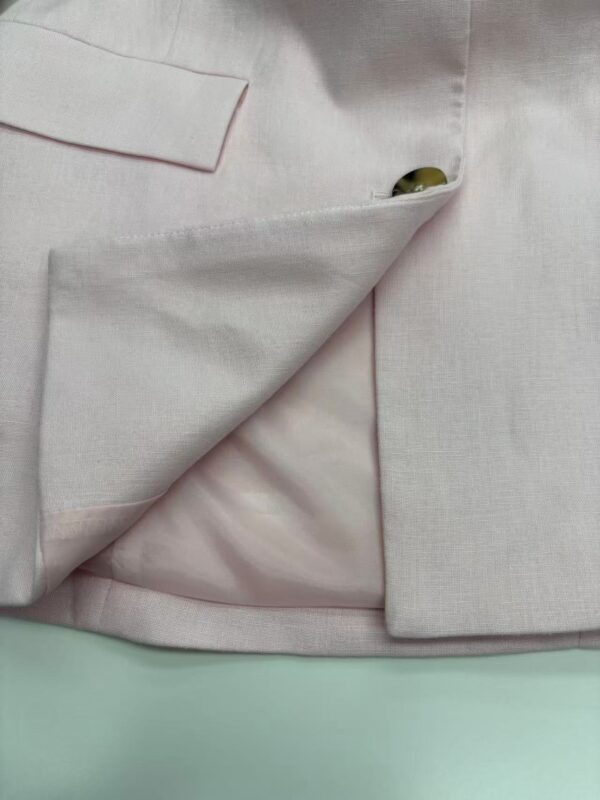 Close-up of a stylish light pink blazer with a lapel and pocket detail, perfect for formal or business casual wear.