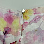Close-up of floral fabric with a small white button at the top, showcasing a delicate, colorful floral pattern in pink, yellow, and purple hues.