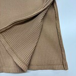 Close-up of beige ribbed knit fabric with a folded edge, showcasing texture and stitching details for fashion and textile focus.