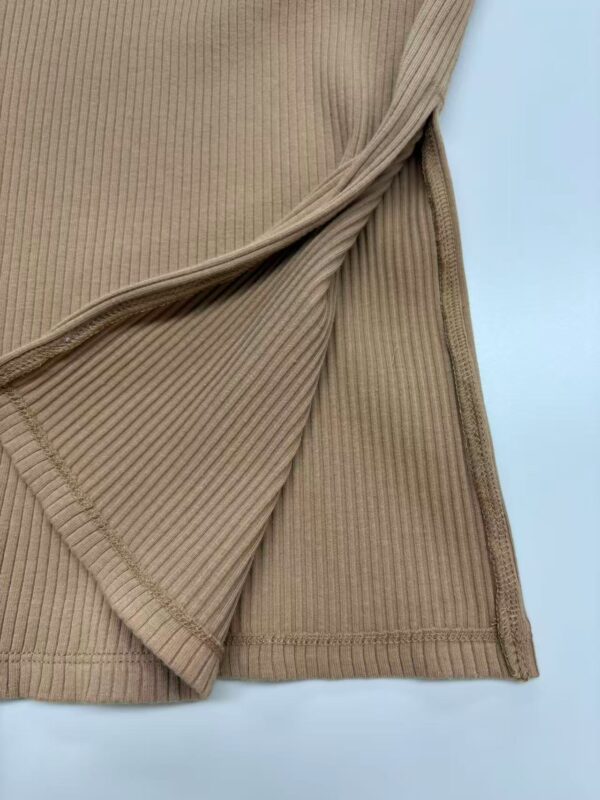 Close-up of beige ribbed knit fabric with a folded edge, showcasing texture and stitching details for fashion and textile focus.