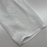 Close-up of a white dress shirt fabric showing texture and a button detail, ideal for formal wear or fashion accessories.