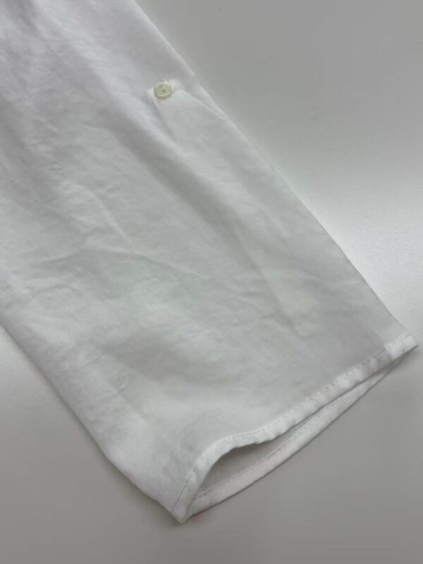 Close-up of a white dress shirt fabric showing texture and a button detail, ideal for formal wear or fashion accessories.